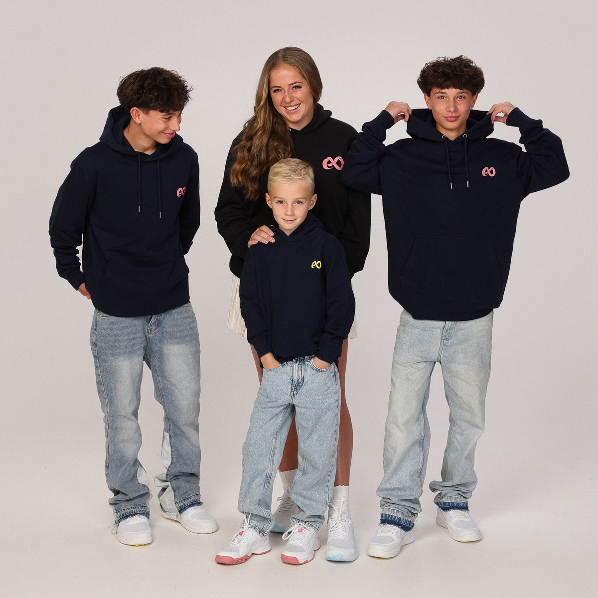 Four children wearing navy hoodies with a logo on a light gray background